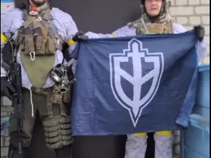Deux combattants armés déploient le drapeau du Corps des volontaires russes