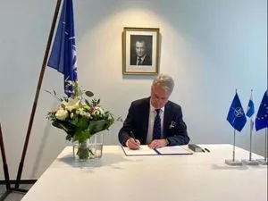 Signature de l’instrument d’adhésion finlandaise, sous un drapeau de l’OTAN