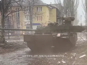 Char russe manœuvrant dans une rue, devant un immeuble aux fenêtres soufflées