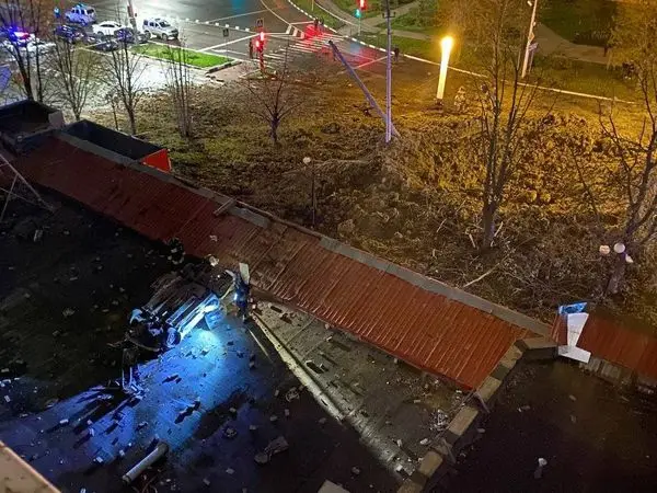 Cratère et voiture retournée dans une rue de Belgorod, la nuit