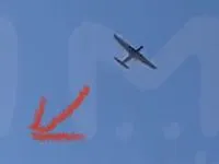Drone à voilure fixe en vol dans un ciel bleu, marquage rouge au sol