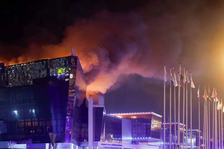 Le Crocus City Hall en flammes dans la nuit, épaisse fumée au-dessus du toit